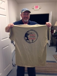 Mike, holding a shirt that says, "Take a Stand to Fight Hunger." The shirt was given to him by a local church group, Heart of a Sportsman.