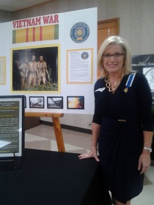 Elizabeth Marxwell Steele Chapter DAR Regent, Kim Edds, in front of a display about the Vietnam War.